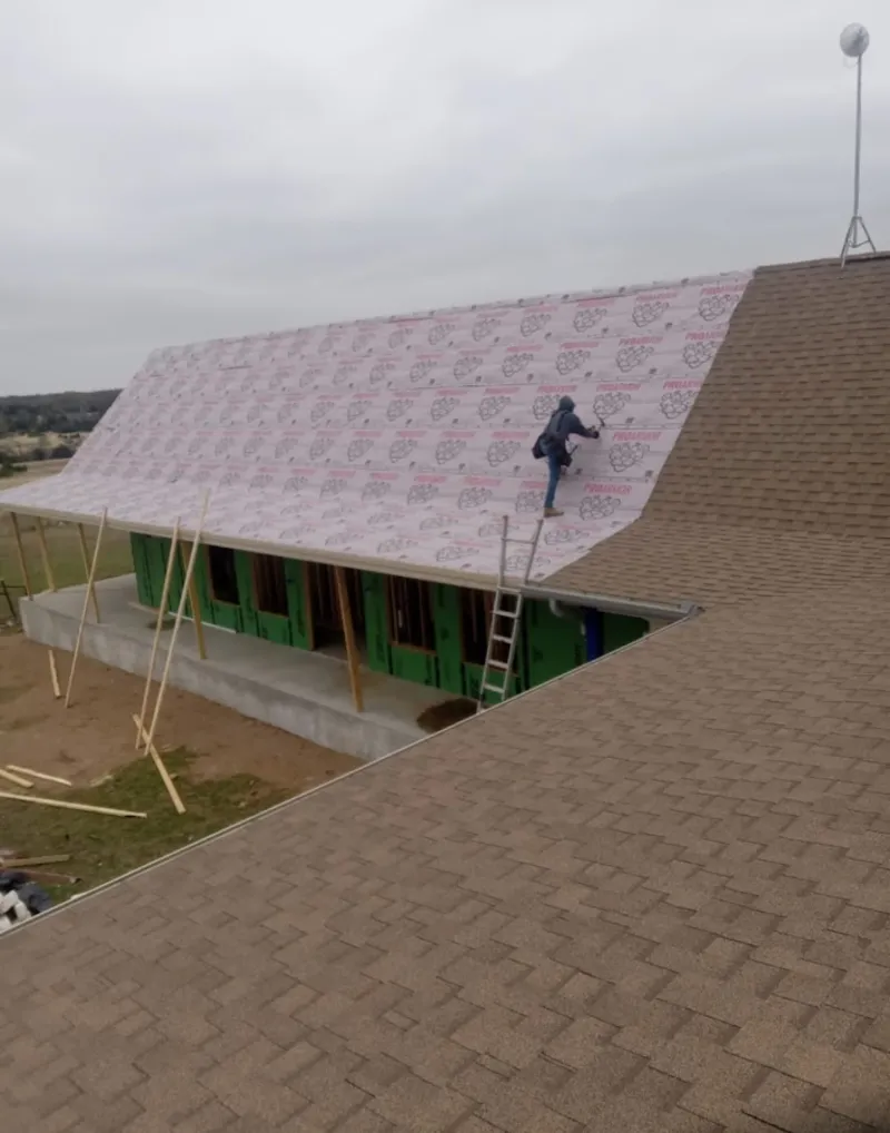 Worker preparing underlayment for a metal roof installation in Athens